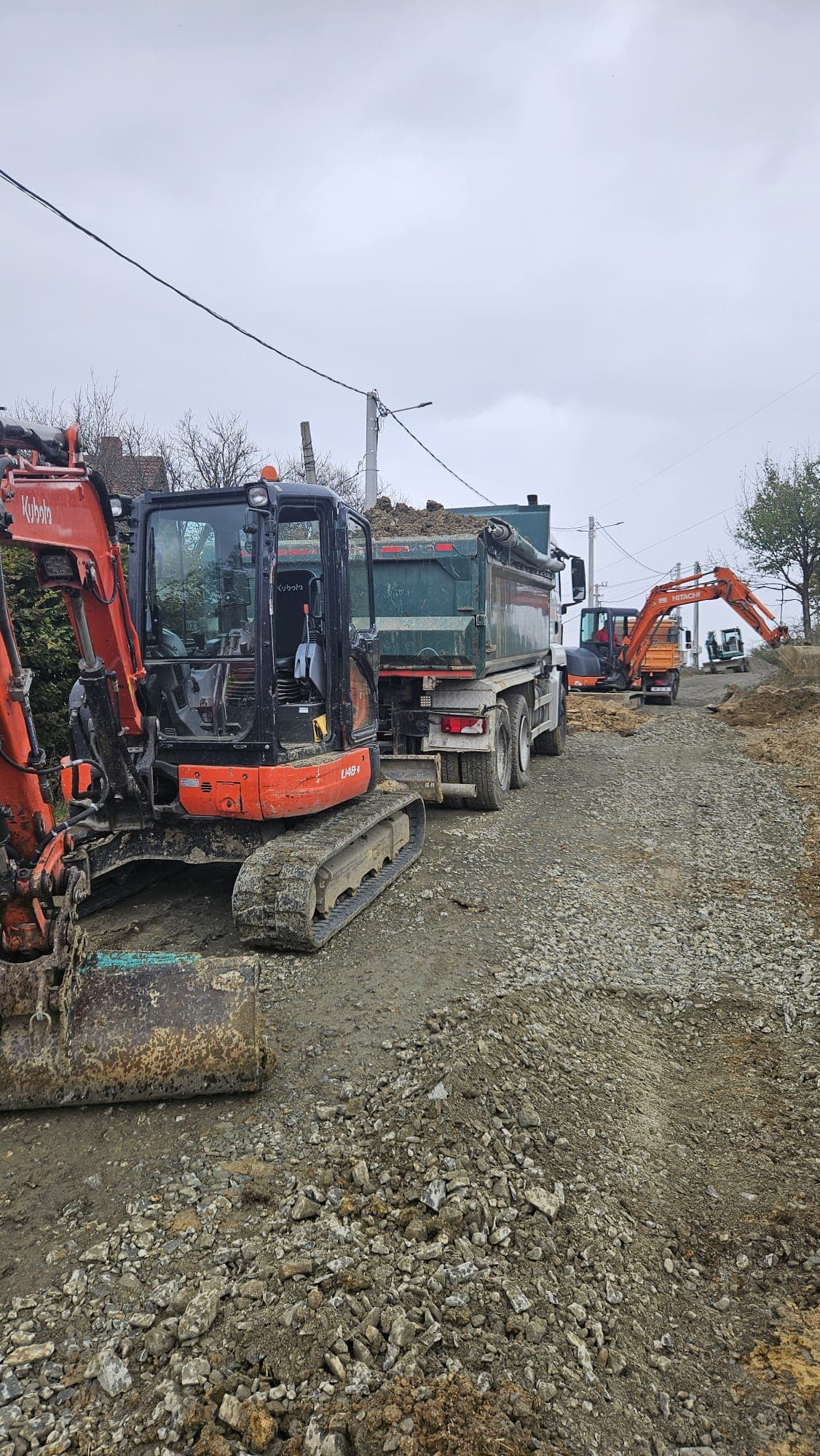 Miniexcavator Kubota U48-4 și autobasculantă HCN Construct pe un drum pietruit din Sibiu