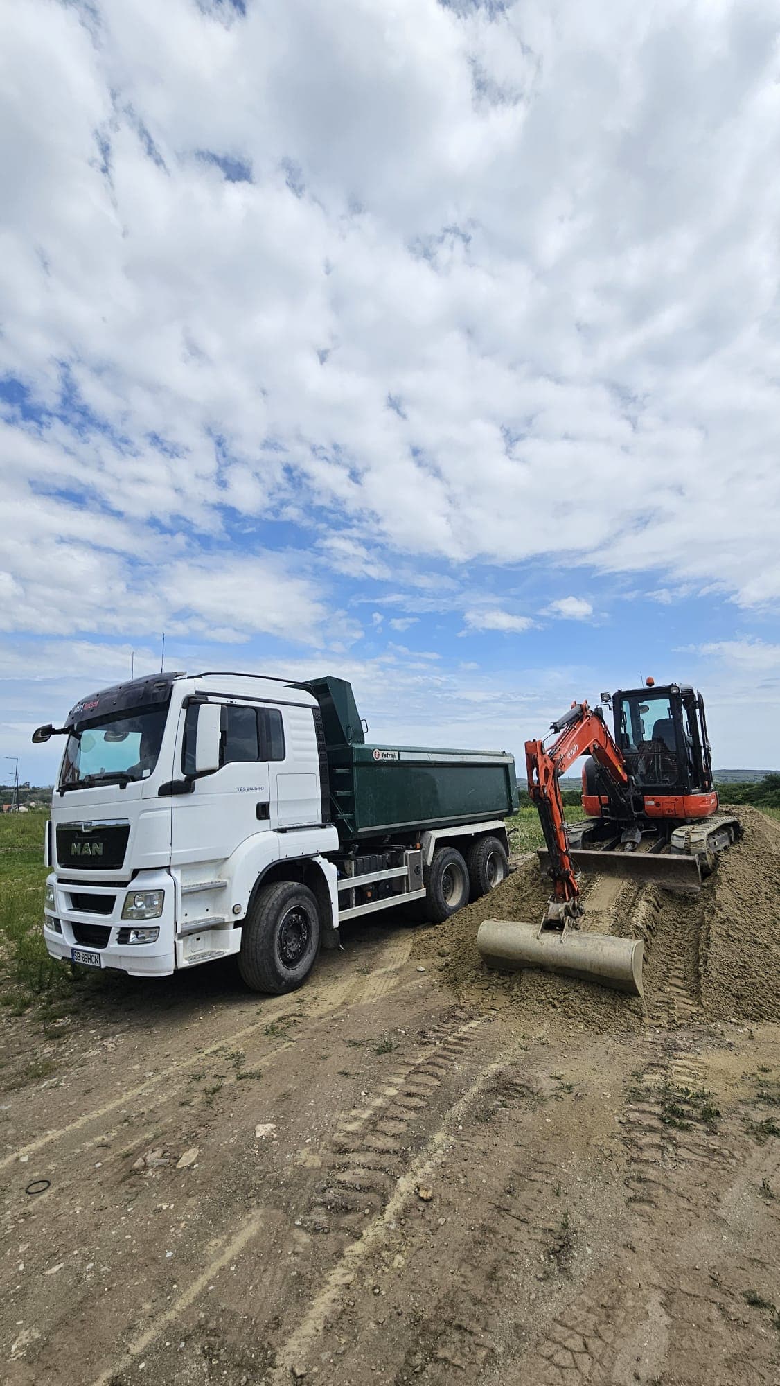 Autocamion MAN cu remorcă transportând un miniexcavator Hitachi al HCN Construct