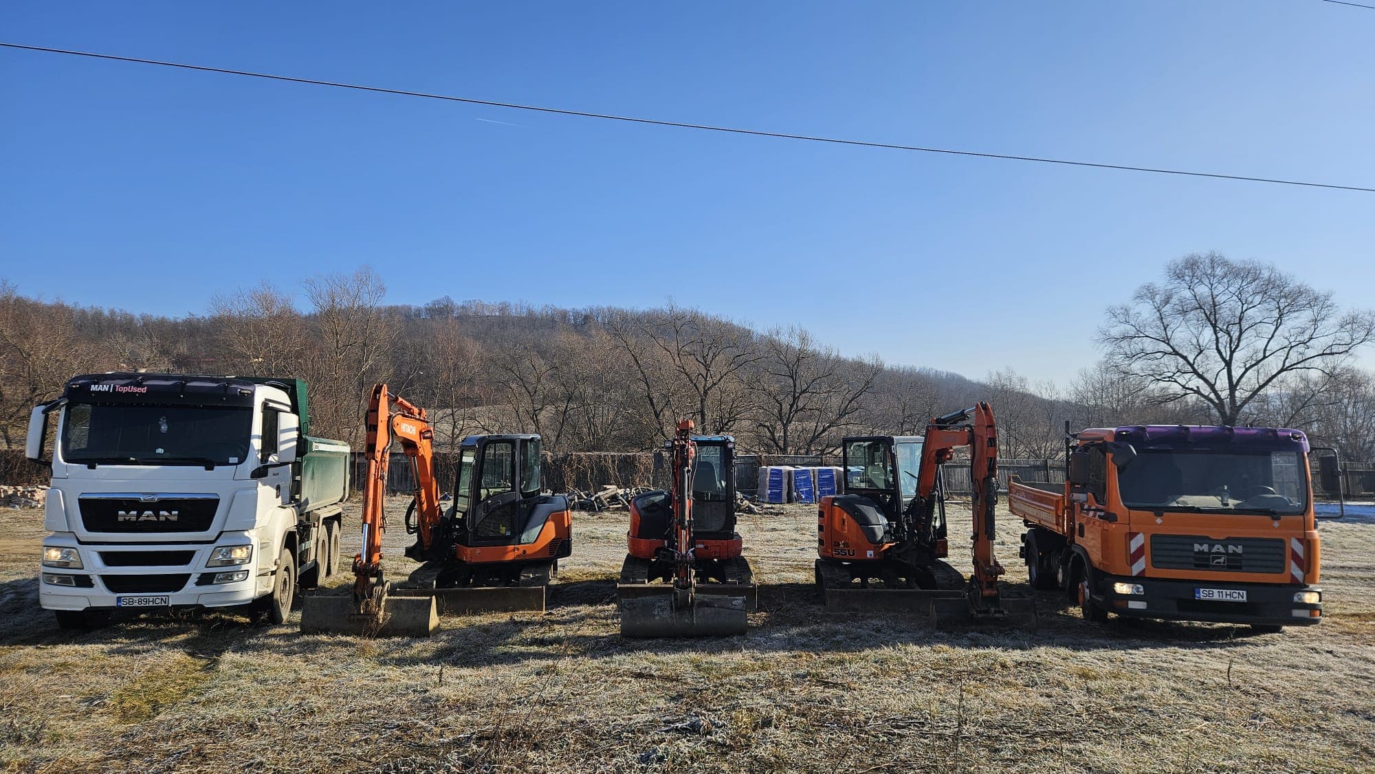 Camion MAN cu remorcă transportând un miniexcavator Hitachi al HCN Construct
